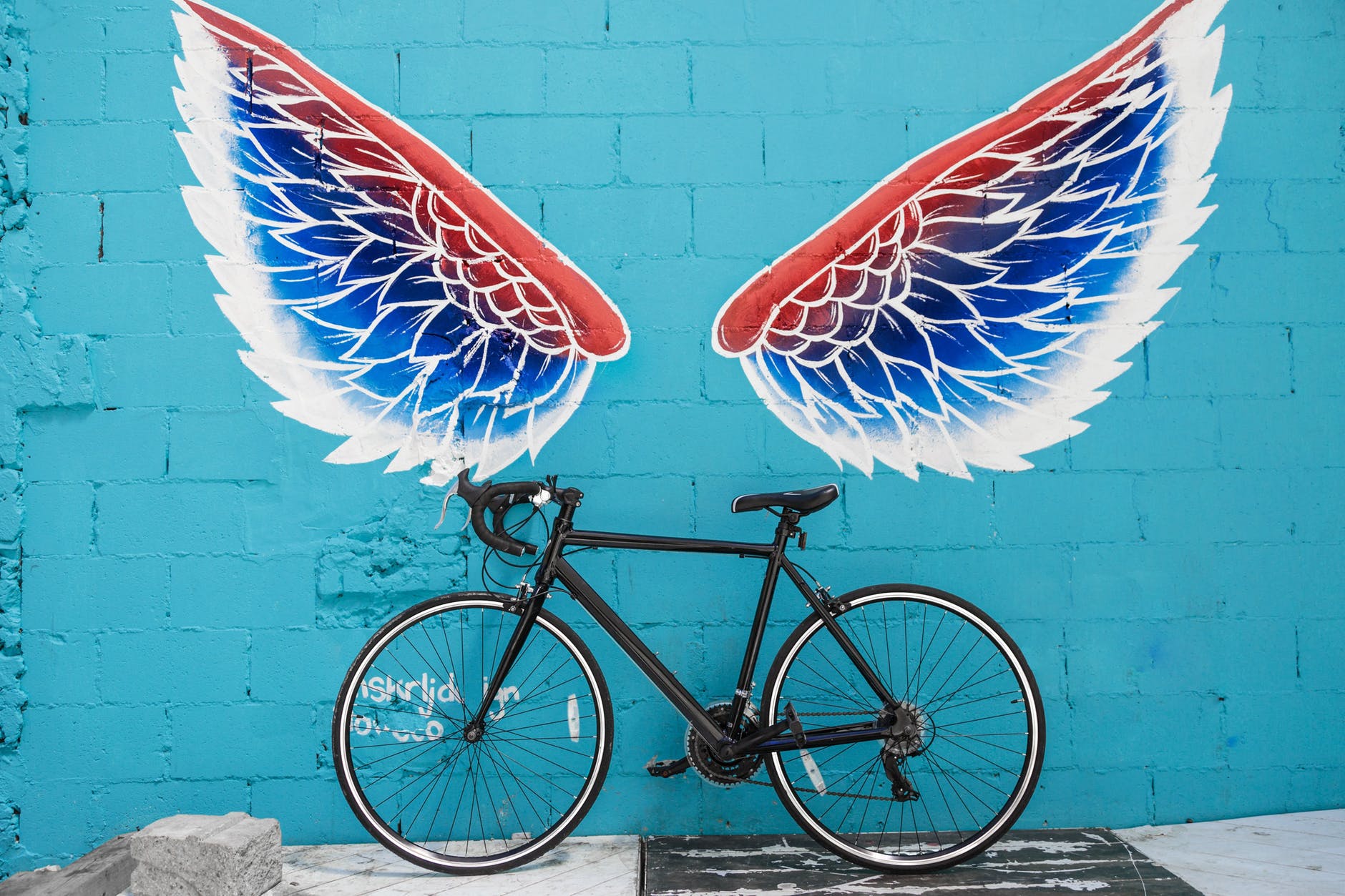 black road bike leaning on red blue and white wing graffiti wall